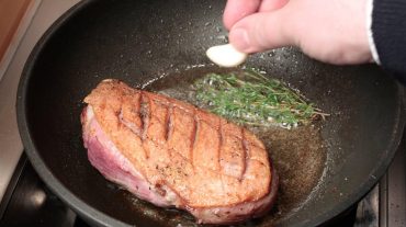 roast duck breast in the pan with herbs and garlic