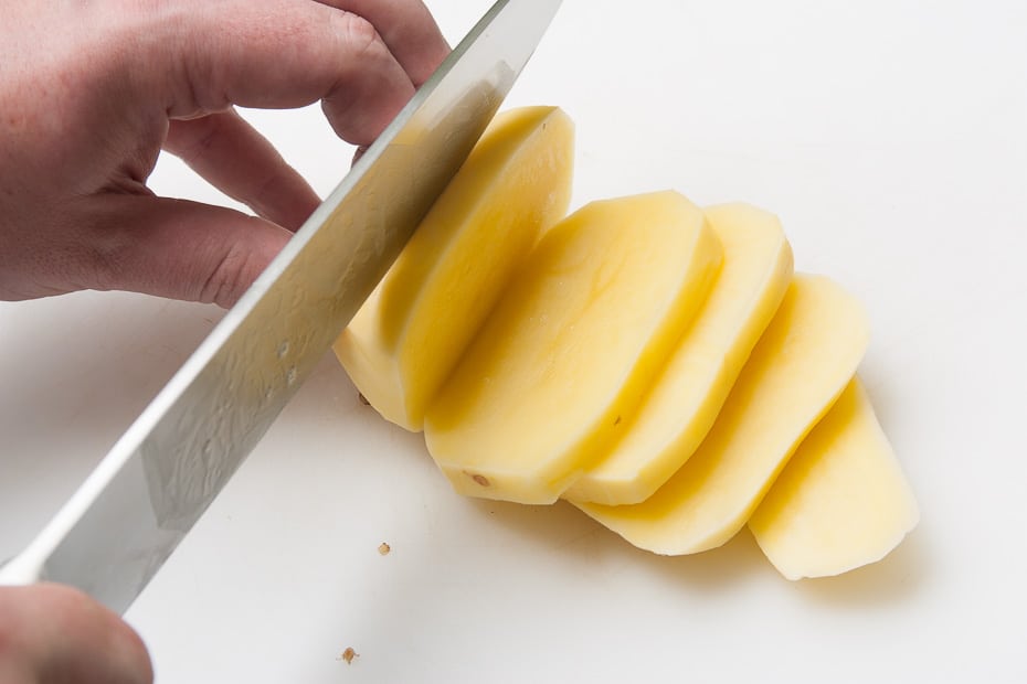 Cut raw, peeled potatoes into slices
