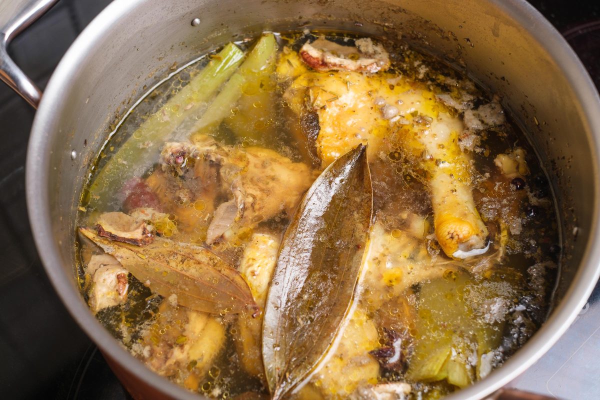 Boiled chicken soup in the pot close-up