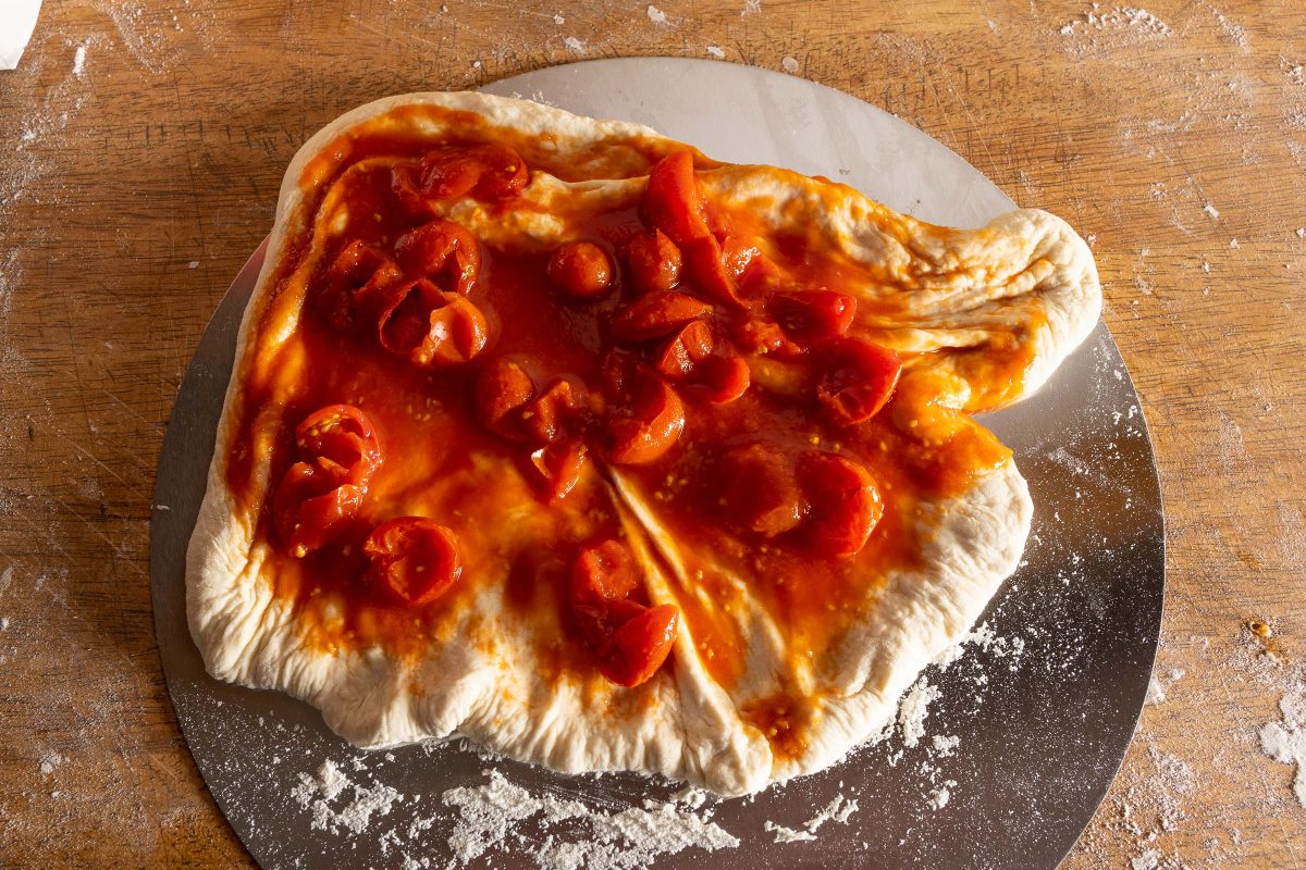 Pizza dough for Pizza Margherita covered with tomato sauce