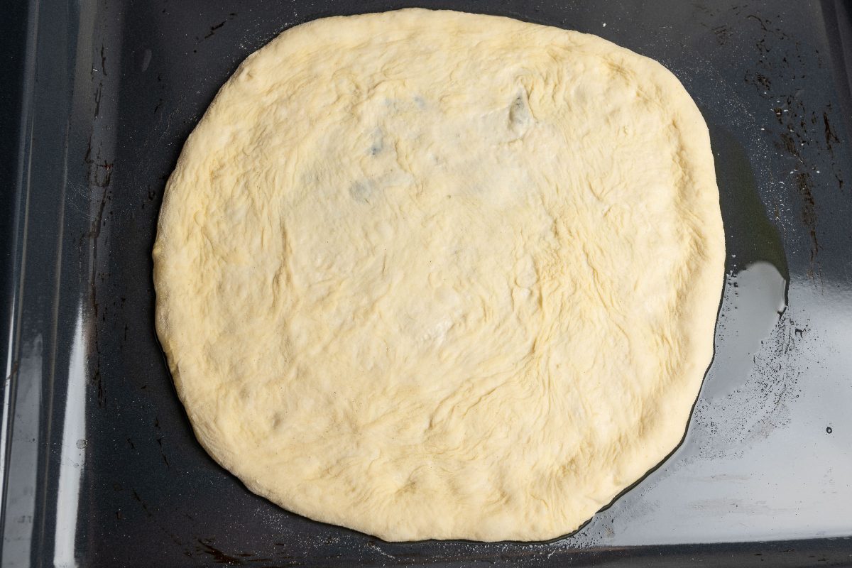 Quattro formaggi Pizza dough shaped on a baking tray