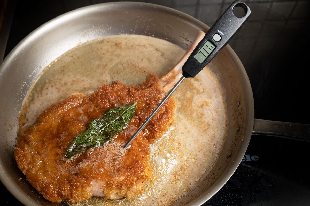 Measure the core temperature of the Cotoletta Milanese in the pan.