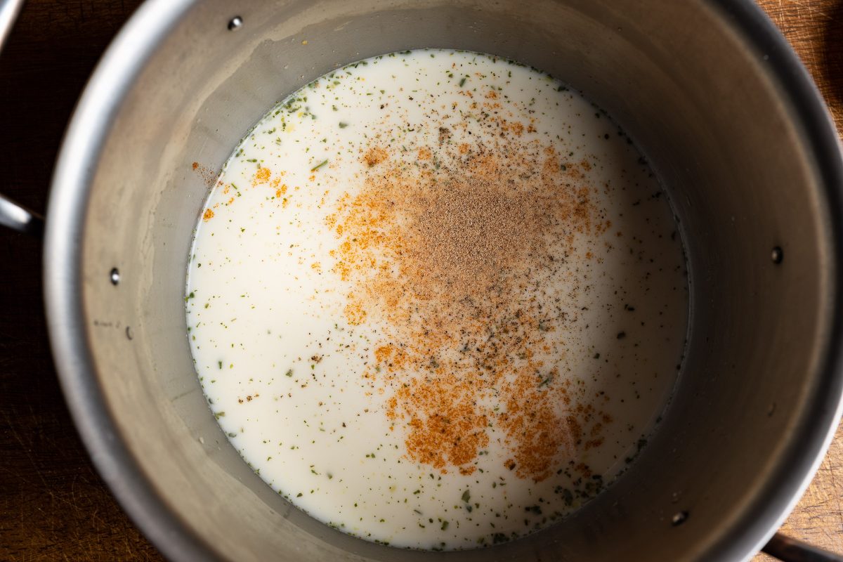 Cream and broth in saucepan with spices