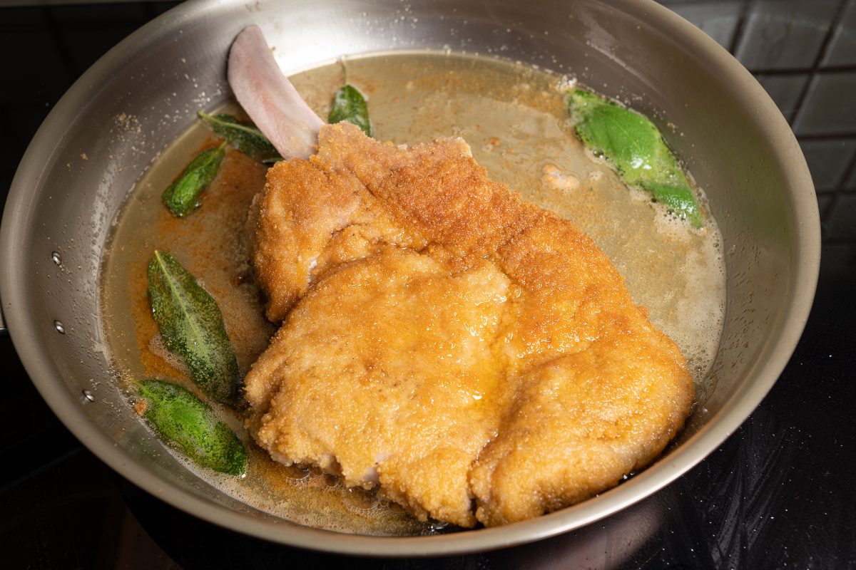 Breaded veal cutlet, Cotoletta Milanese, in the pan with sage leaves